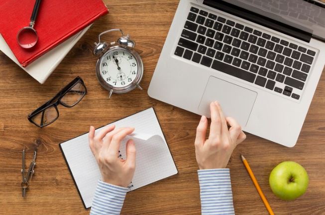 Student practicing GMAT Quant time management with a laptop, notebook and clock
